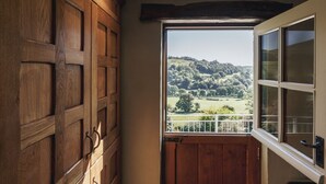 A wooden door with a view of a green landscape through a window.