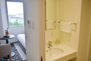 Ein Badezimmer mit Waschbecken, Spiegel, Handtuchhalter und einem Fenster mit Blick auf Gebäude.