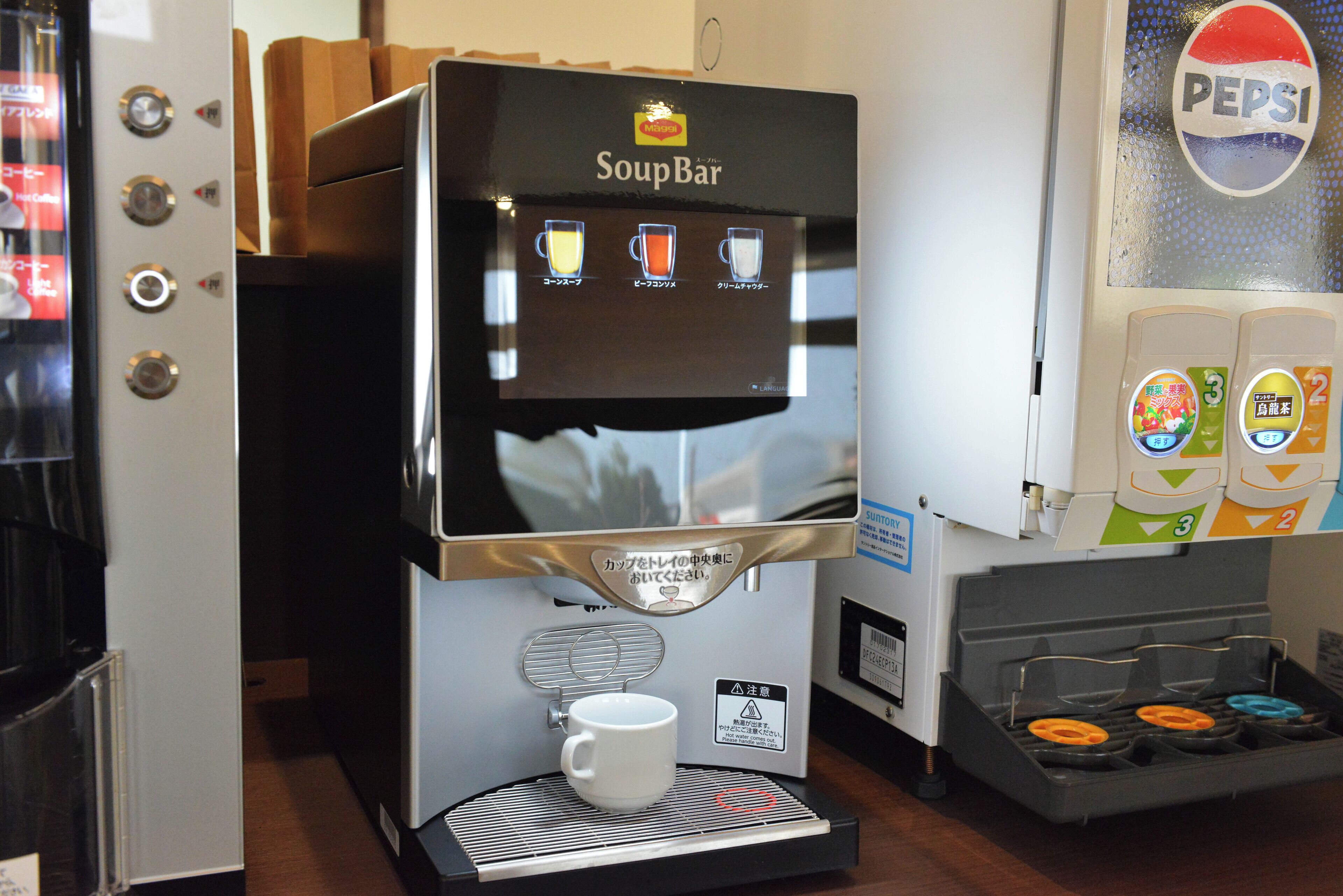 A coffee machine with a menu screen and a cup holder.