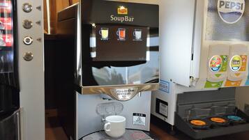 A coffee machine with a menu screen and a cup holder.