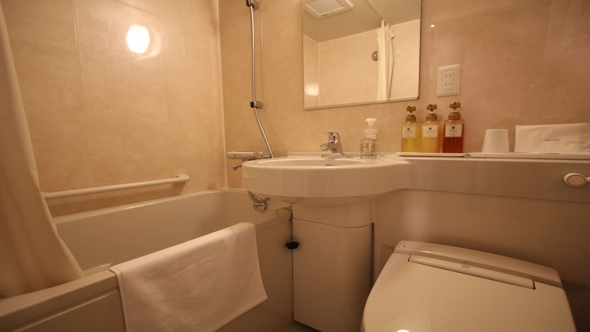 A bathroom with a bathtub, a sink, a toilet, and a mirror.