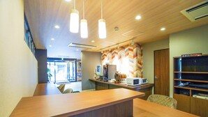 Un área de recepción moderna con un mostrador de madera, iluminación colgante y un revestimiento de pared con diseño.