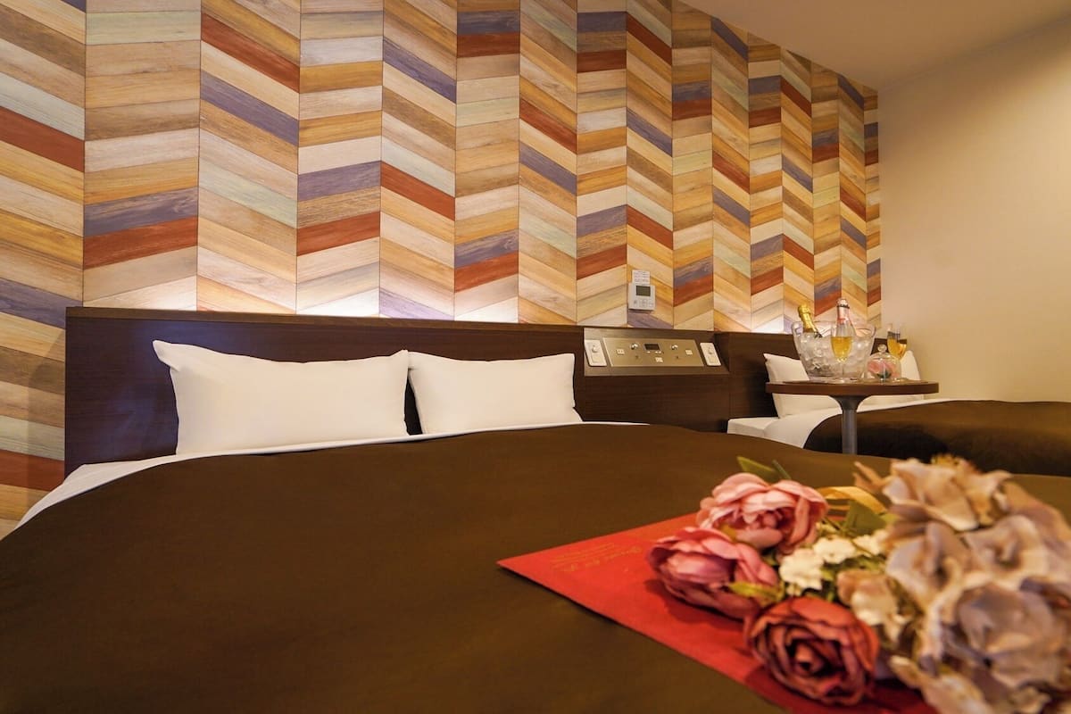 A hotel room with a large bed, a nightstand, a control panel, and a wall with a chevron pattern.