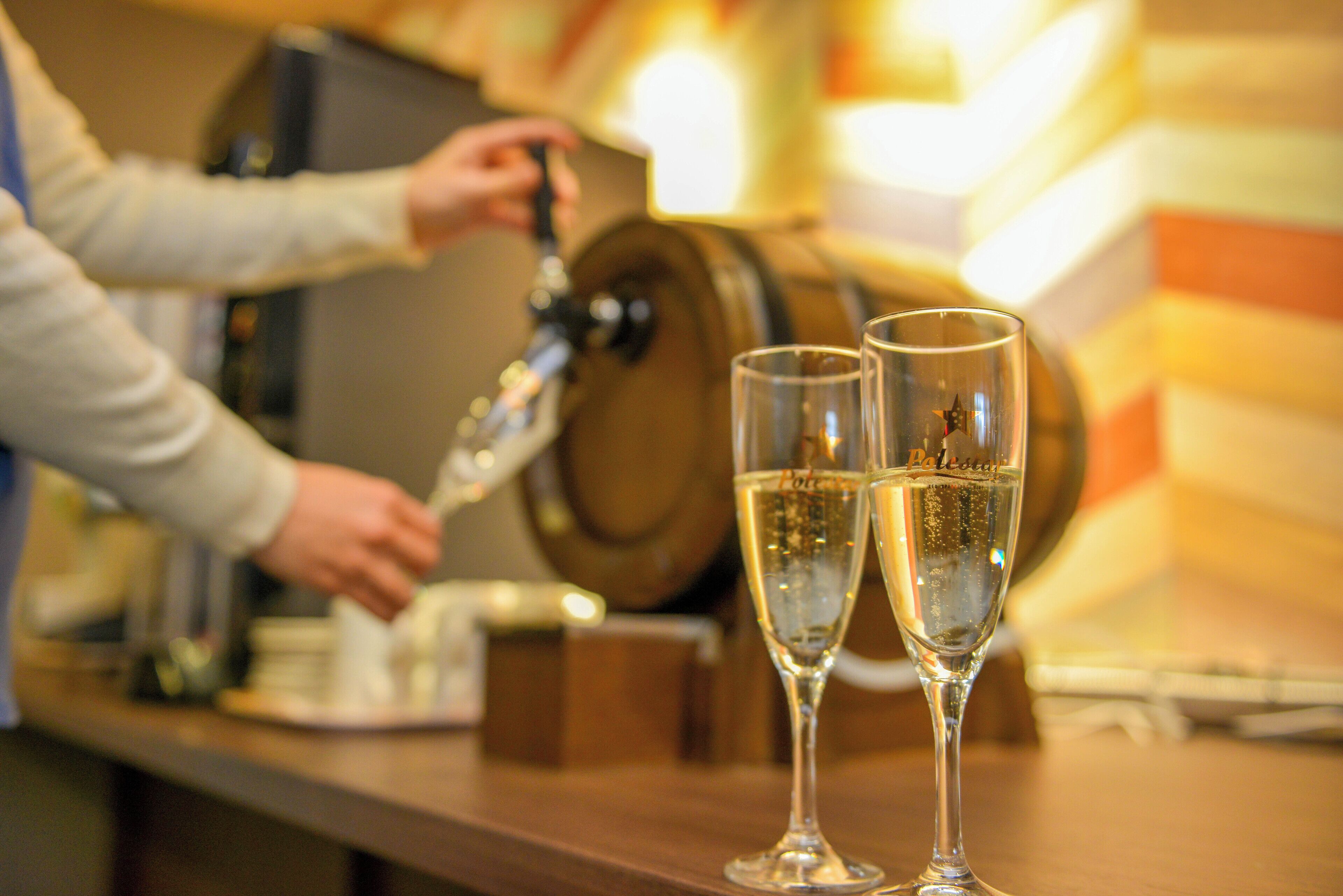 Een bar met twee champagneglazen en een persoon die van de tap schenkt.