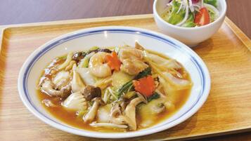 A plate of soup with vegetables and meat, and a side salad on a wooden tray.