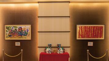A room with two framed artworks, a red table with two lion statues, and a marble floor.