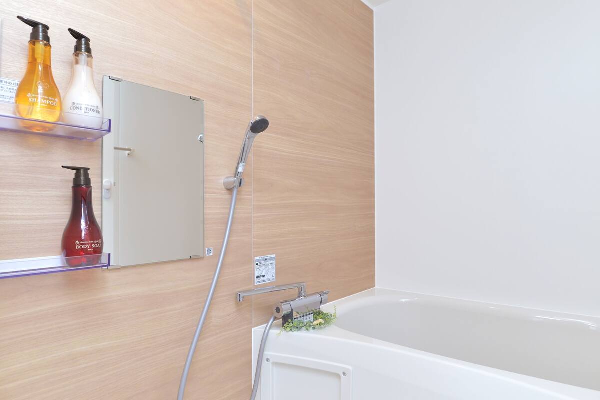 A bathroom with a bathtub, a showerhead, and shelves with toiletries.