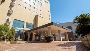 Un hotel de diseño moderno, con un amplio dosel de entrada, varios pisos y un cielo despejado.
