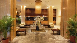 Vestíbulo de hotel con recepción, zona de estar y arreglos florales decorativos.