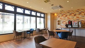 Un café moderne avec de grandes fenêtres, des tables et des chaises en bois.