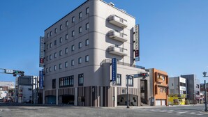 Un hôtel à plusieurs étages doté d’une architecture moderne, avec des balcons aux étages supérieurs et une entrée au niveau du sol.