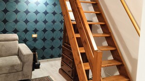 A wooden staircase with a handrail, a patterned wall, a sofa, and a rug in a room. - Piazzetta 4 - Holiday Home (Napoli)