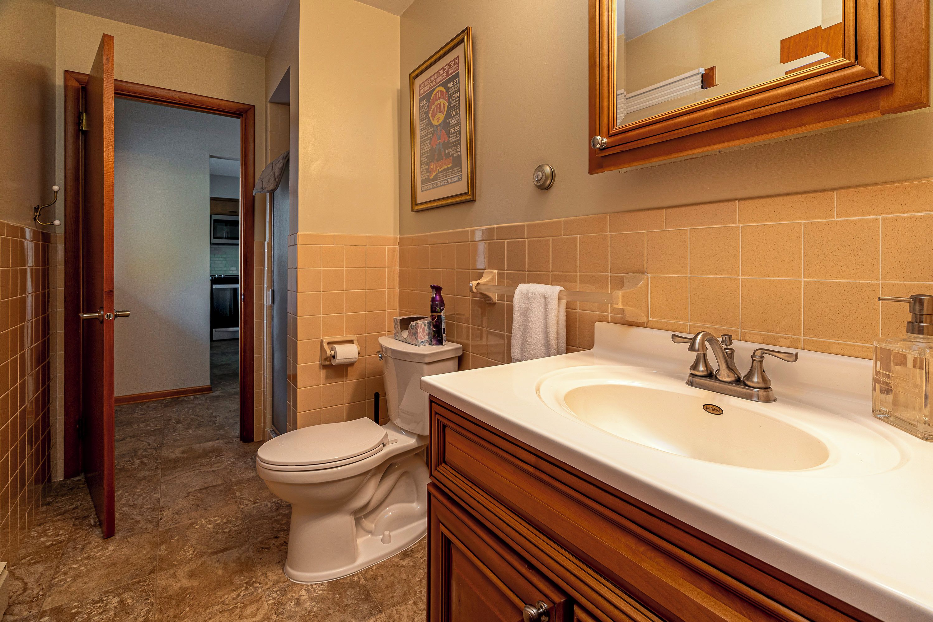 A bathroom with a toilet, sink, and mirror.