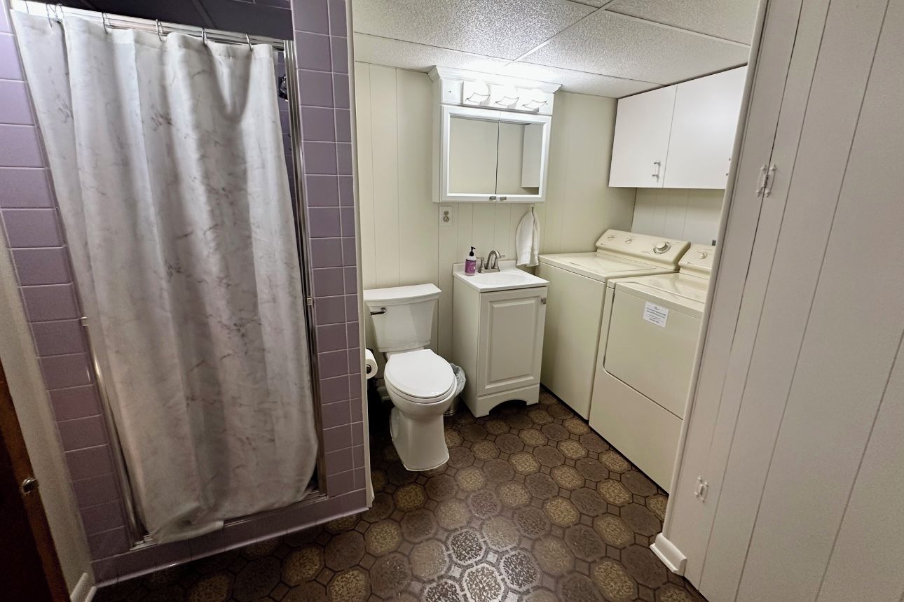 A compact bathroom with a toilet, sink, and a washing machine.