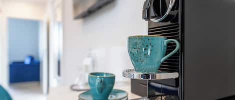 A compact espresso machine with a teal cup and saucer on its drip tray.