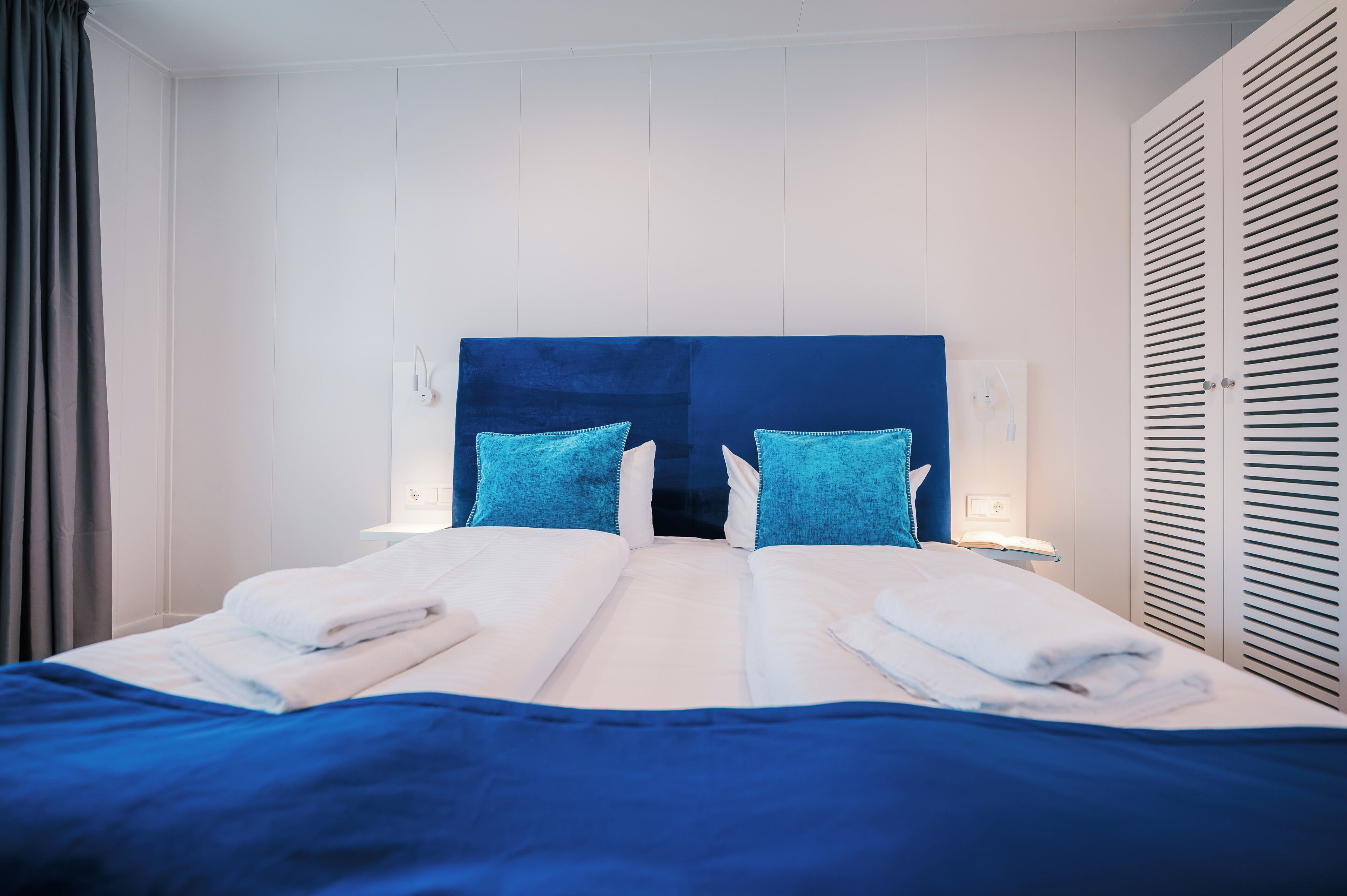 Una habitación de hotel con una cama grande, dos almohadas, una mesita de noche y un armario.