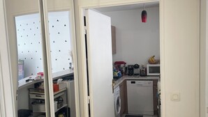 Een kleine keuken met een wasmachine, een magnetron en een klein aanrecht.