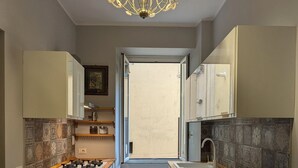 A kitchen with white cabinets, a wooden countertop, and a chandelier.