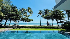 A pool with a clear view of the ocean and palm trees.