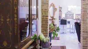 A room with a wooden cabinet, a mirror, a table with a notebook, a vase with flowers, and an archway leading to another room.