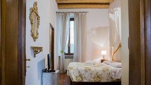 A bedroom with a bed, a nightstand, a mirror, and a window with curtains.