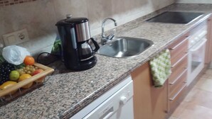 Una cocina con encimeras de granito, cafetera, lavabo y lavavajillas.