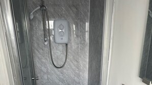 A bathroom with a glass-enclosed shower, a white sink with a soap dispenser, and a mirror above the sink.