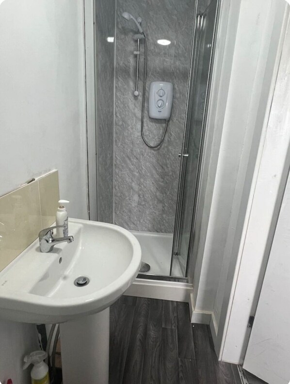 A bathroom with a white sink, a shower with a control panel, and a tiled floor. - Oak Tree Lane Luxury Apartment in Birmingham (Birmingham)