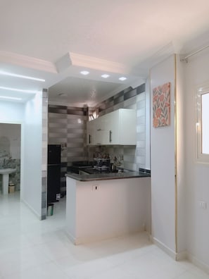 A modern kitchen with white cabinetry, a black refrigerator, and a tiled backsplash.