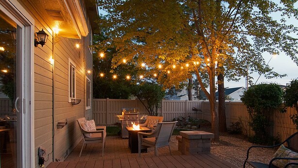 An outdoor patio with a fire pit, seating, and string lights. - Spacious Getaway, Perfect for Groups, Fire pit, BBQ, 70" TV, near The Village, TopGolf, Parks (Meridian)