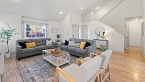 A spacious living room with two grey sofas, a coffee table, and a wooden chair. - Spacious Getaway, Perfect for Groups, Fire pit, BBQ, 70" TV, near The Village, TopGolf, Parks (Meridian)