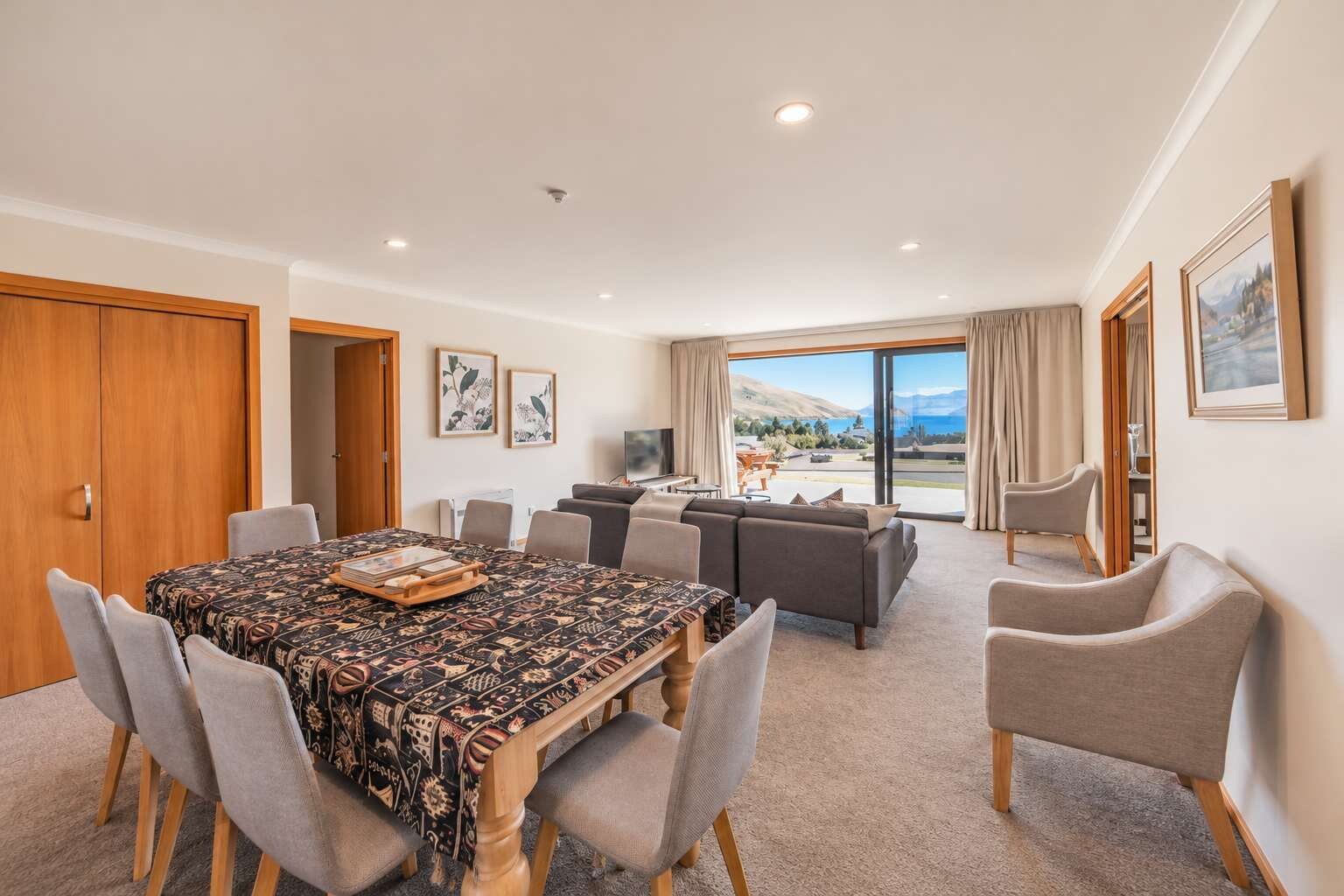 A spacious living area with a dining table, sofas, and a large window offering a scenic view.