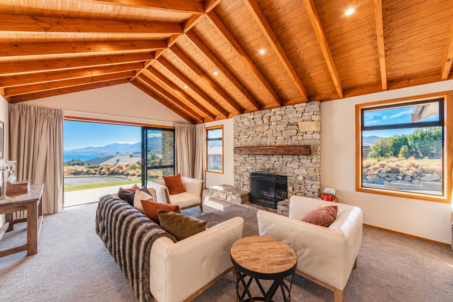 A spacious living room with a stone fireplace, leather sofas, and a view of the outdoors.