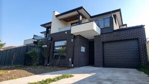 A modern two-story house with a garage, a balcony, and a small garden area. - Brand new House in Sunshine West (Sunshine West)