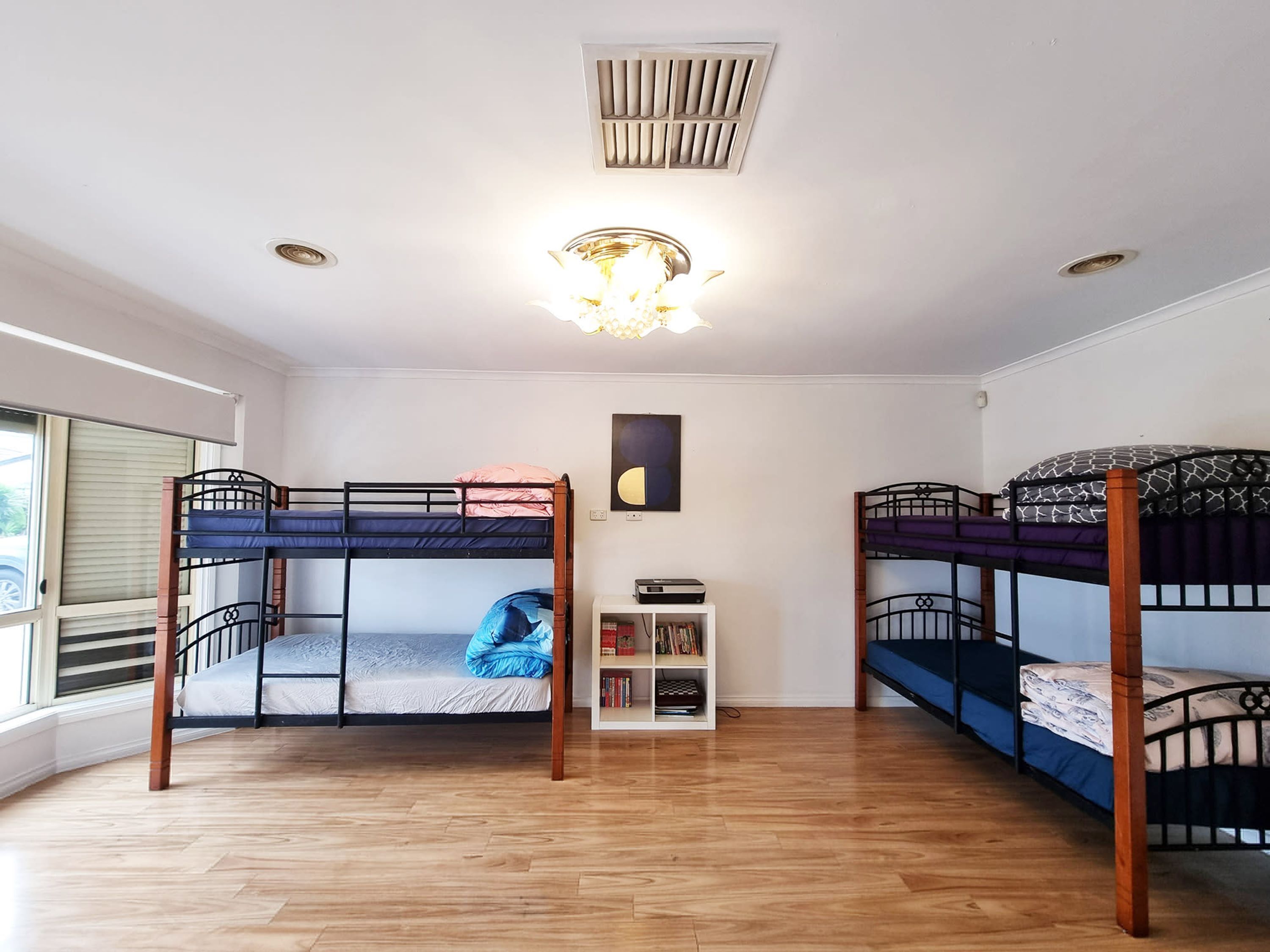Una habitación con dos literas, una estantería y una lámpara en el techo.
