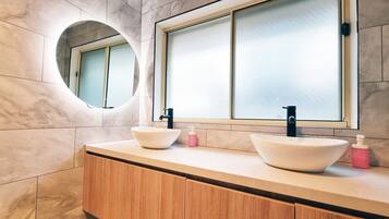 A bathroom with two sinks, a mirror, and a window.