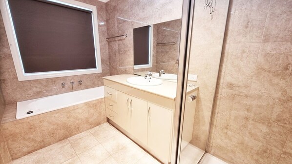 Un baño moderno con bañera, dos lavamanos y cabina de ducha de vidrio.