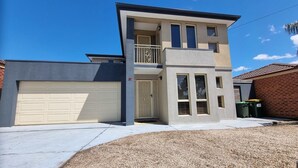 A two-story residential building with a garage, a balcony, and a small front yard. - St Albans House - Spacious and Modern Home (St. Albans)