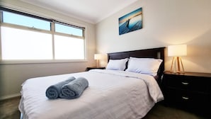 A hotel room with a large bed, two bedside tables with lamps, a painting on the wall, and a window providing natural light. - St Albans House - Spacious and Modern Home (St. Albans)