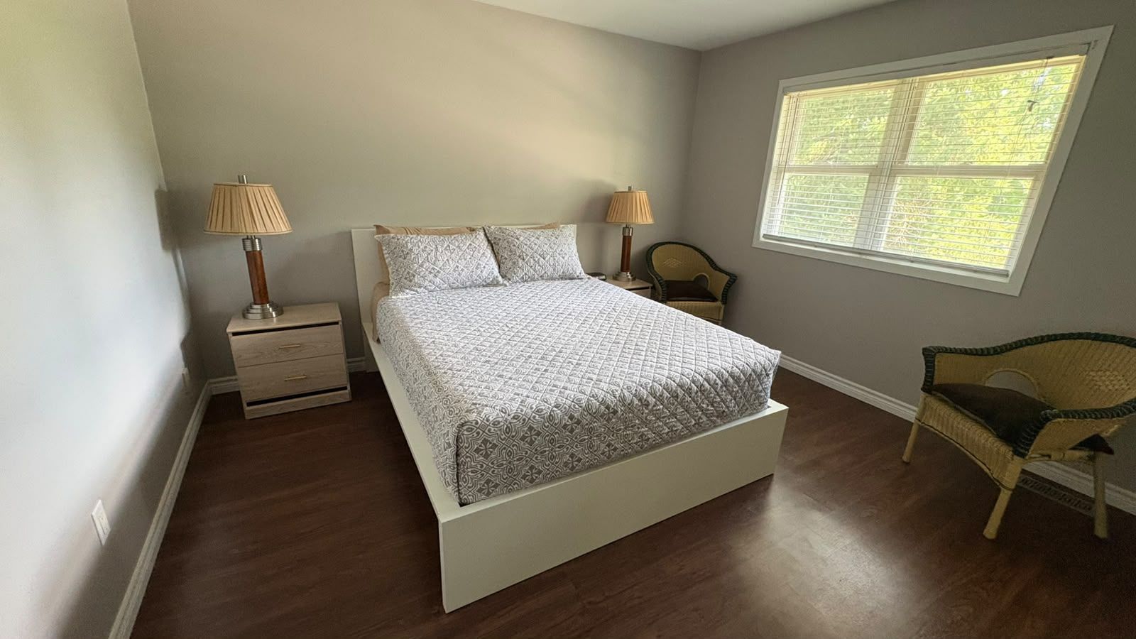 Une chambre à coucher avec un lit, deux tables de chevet, une chaise et une fenêtre.