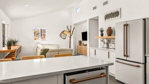Une cuisine moderne avec des meubles blancs, un îlot central et un lave-vaisselle encastré.