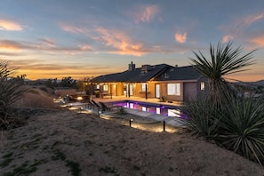A house with a swimming pool, outdoor seating, and a desert landscape.
