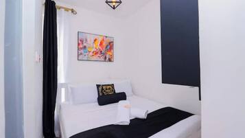 Une chambre à coucher avec un lit, une décoration aux couleurs noir et blanc, un tableau au mur et un luminaire suspendu.