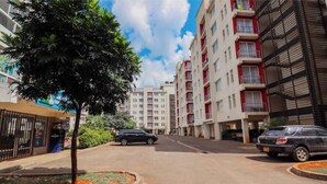 Un edificio residenziale con diversi piani, balconi e un'area di parcheggio con auto.