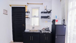 Una cucina compatta con pensili e basi nere, un lavello, un piano cottura e un frigorifero.