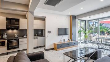 A modern kitchen with built-in appliances, a dining area with a glass table, and a view of the outdoors.