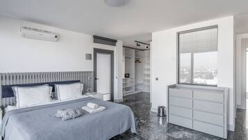 Ein modernes Schlafzimmer mit Bett, Nachttischen, begehbarem Kleiderschrank und einem Fenster mit Jalousien.