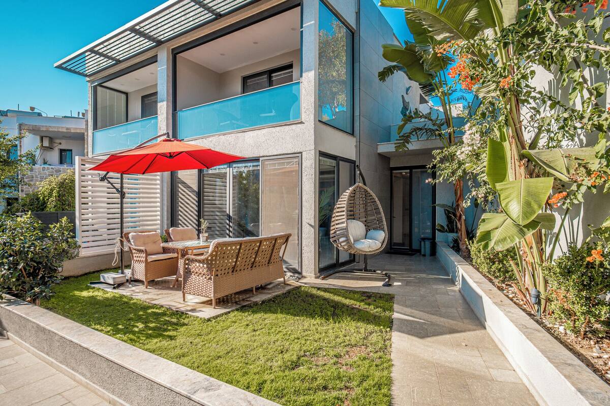 Un bâtiment moderne à deux étages, doté d’un balcon, d’un espace extérieur aménagé pour s’asseoir et d’un fauteuil suspendu.