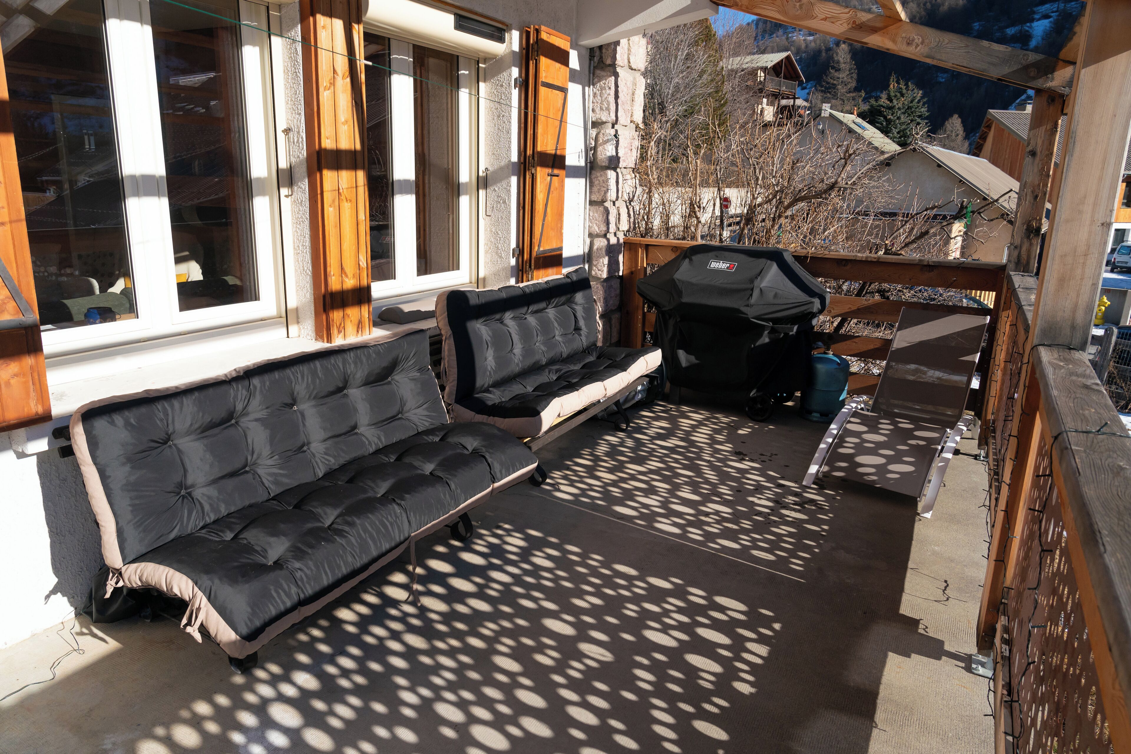 A covered outdoor seating area with a sofa and grill.