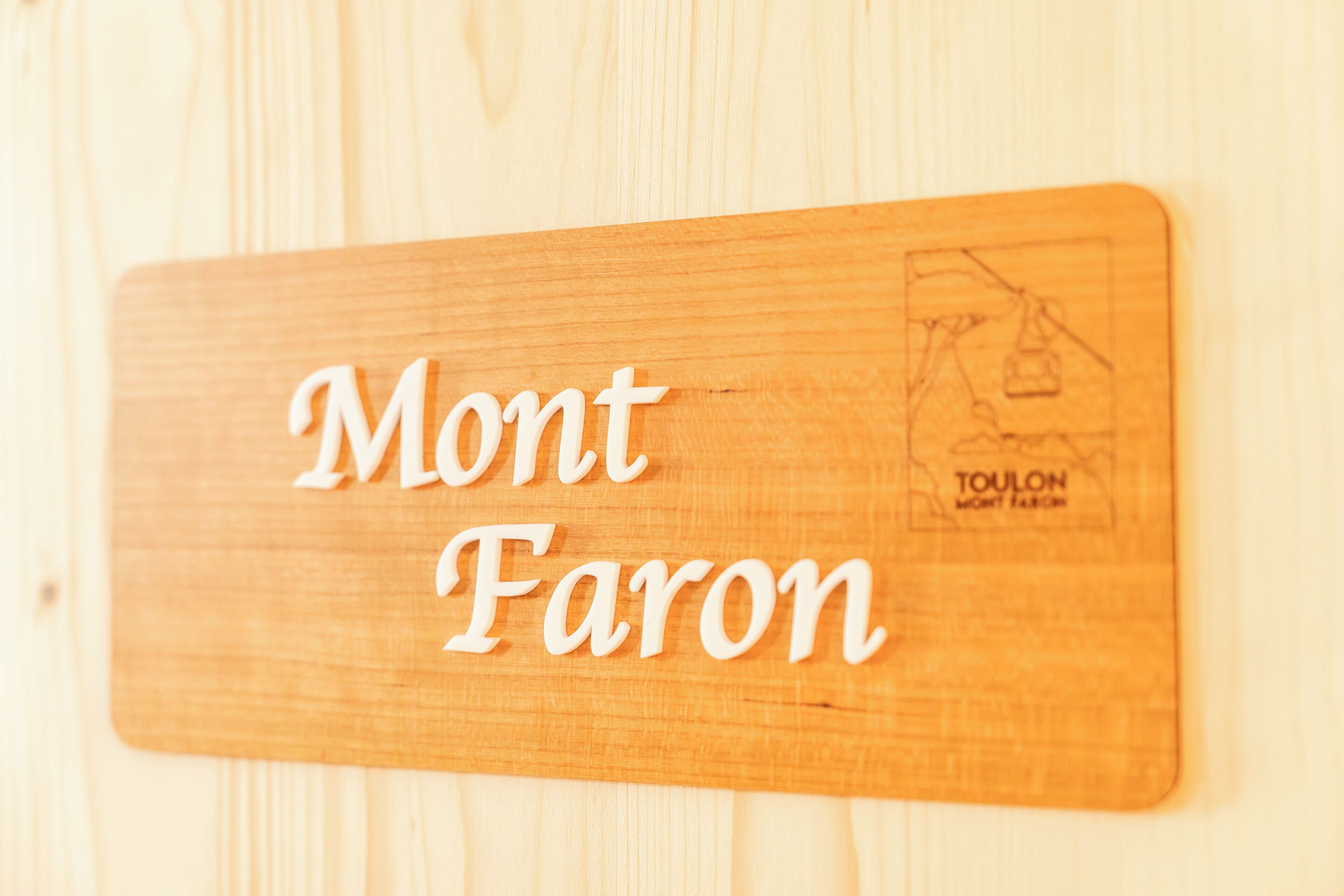 Un panneau en bois portant l’inscription « Mont Faron » et un petit logo.